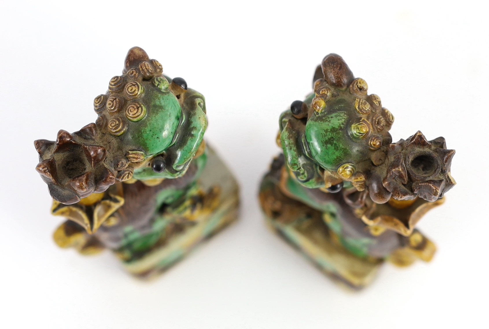 A pair of Chinese sancai-glazed biscuit Buddhist lion joss stick holders, Kangxi period, 15.5 and 16cm high, some restoration